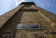 a photograph of the lighthouse tower, shot from below, including a sign that says 'Lighthouse 1864'